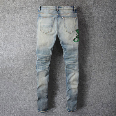Hellblaue Distressed Jeans mit grüner Schlangenstickerei