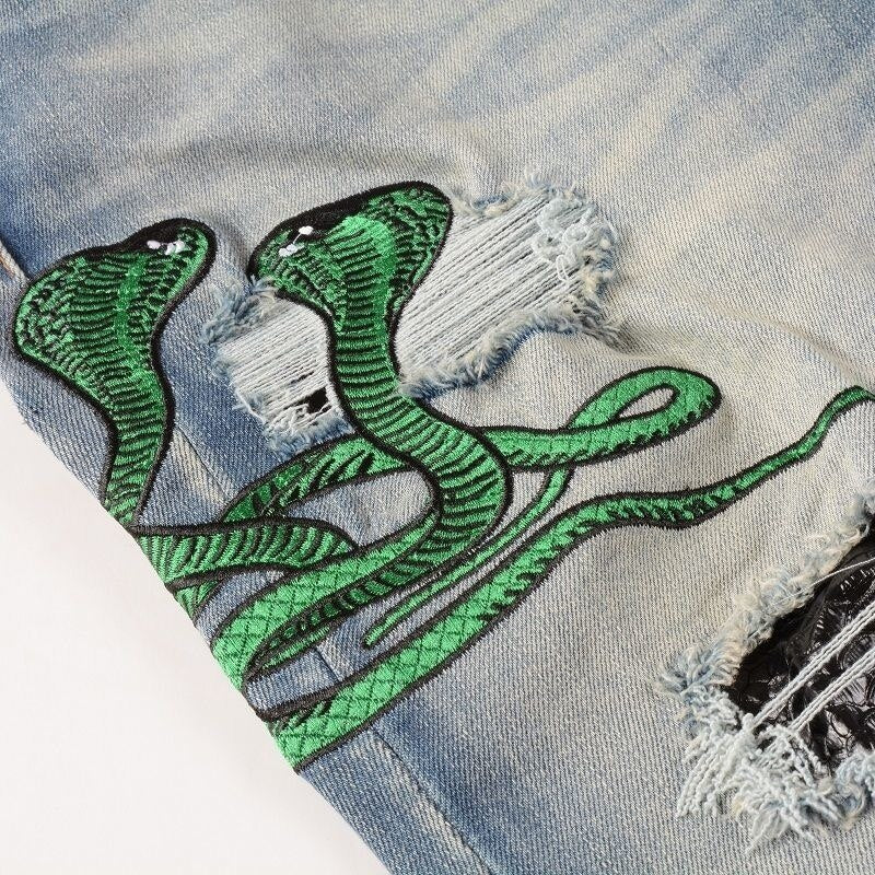 Hellblaue Distressed Jeans mit grüner Schlangenstickerei