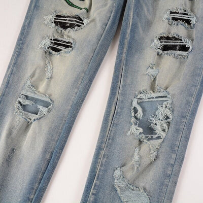 Hellblaue Distressed Jeans mit grüner Schlangenstickerei
